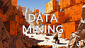 Data Mining, ein Steinbruch mit orangen Containern in einer felsigen Landschaft